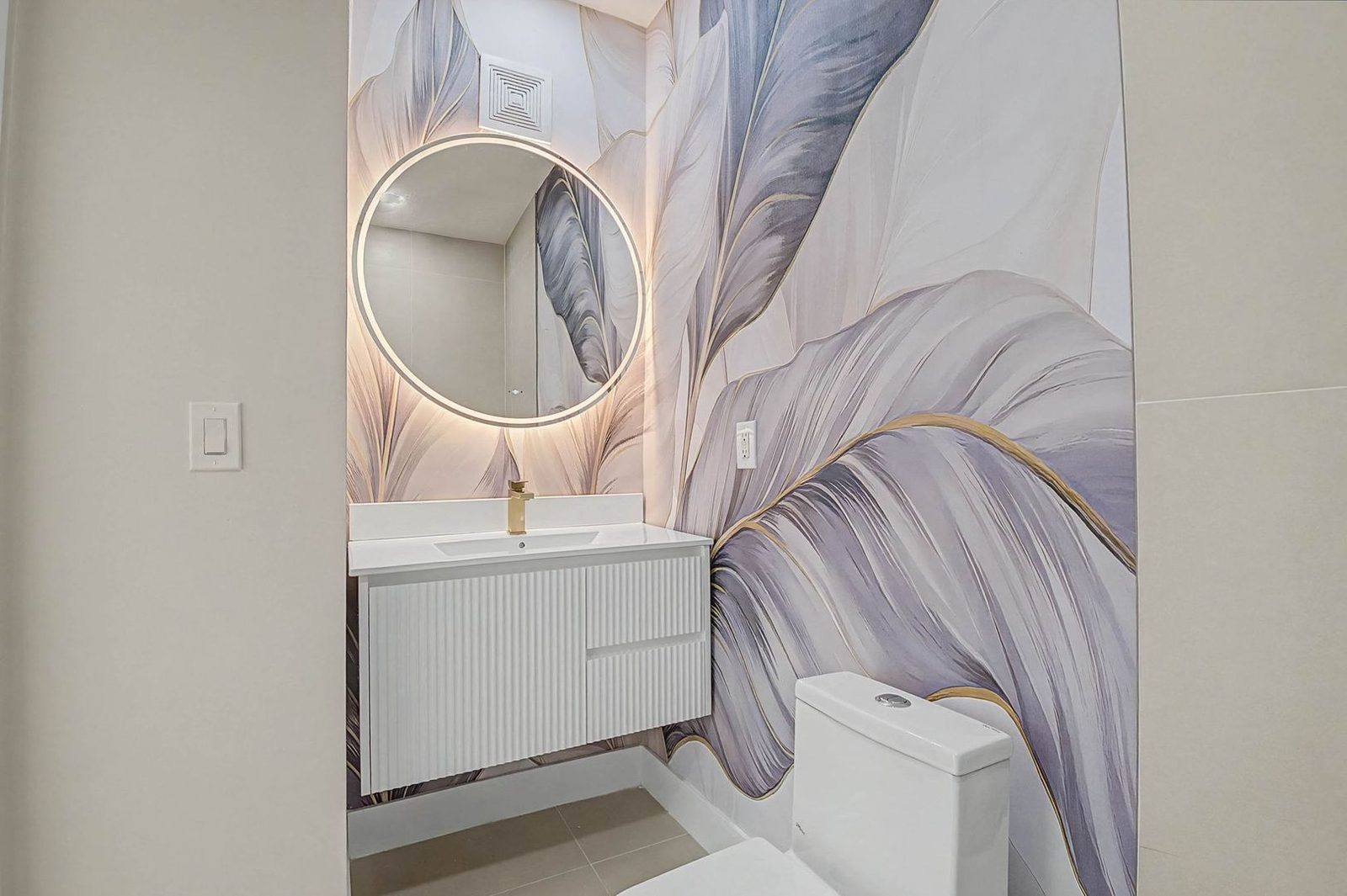 Designer bathroom with backlit round mirror and botanical wallpaper