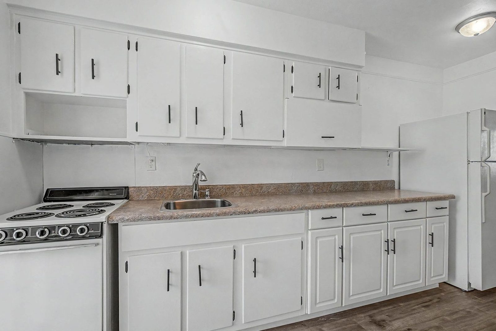Pass-through kitchen with white cabinetry and full-size appliances